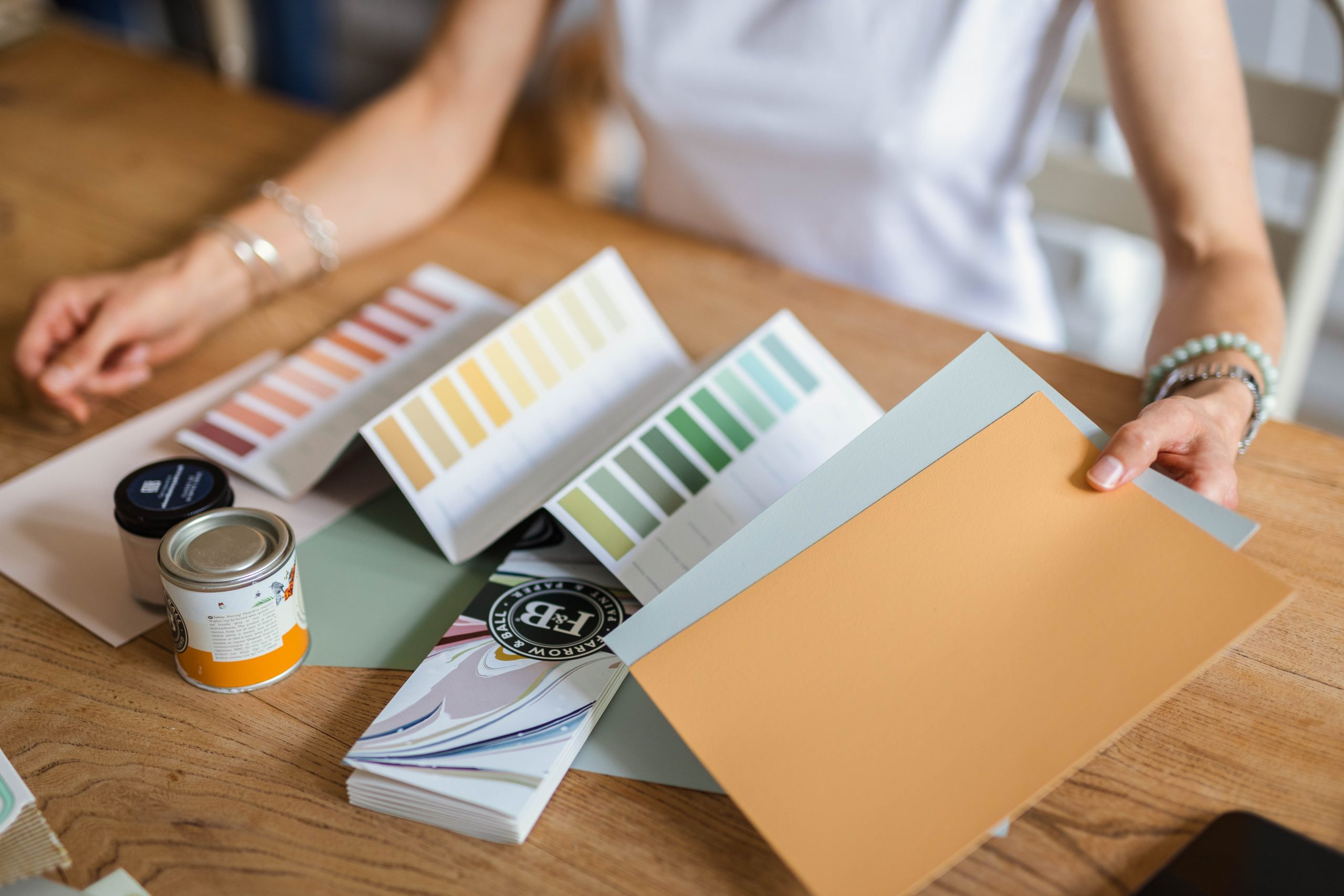 A Colour Consultant looks through paint colour charts and reflects on paint colour options fr a clients room scheme