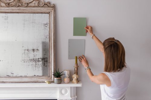 A Colour Consultant holding up two paint colur cards to show how the paint colour would look in the living room